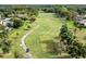 Aerial view of a lush golf course with well-manicured fairways, scattered trees, and golf carts on the path at 20 Iris Pl, Oldsmar, FL 34677