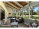 Inviting screened porch with wicker furniture, ceiling fan, and a beautiful view of the landscaped backyard at 20 Iris Pl, Oldsmar, FL 34677