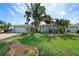 Charming home featuring a light-blue exterior, lush landscaping, and mature palm trees at 2310 Sunrise Se Dr, St Petersburg, FL 33705
