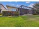 Home's backyard features screened lanai, lush lawn, and mature landscaping at 2632 Tarragona Way, Wesley Chapel, FL 33543
