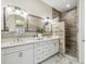 Bright bathroom featuring double sinks, modern fixtures, decorative mirrors, and a tiled walk-in shower at 2632 Tarragona Way, Wesley Chapel, FL 33543