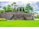 Beautiful community entrance featuring stone waterfalls, lush greenery, and elegant signage at 2632 Tarragona Way, Wesley Chapel, FL 33543