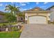 Charming front exterior with a brick driveway, a two-car garage, and lush landscaping at 2632 Tarragona Way, Wesley Chapel, FL 33543
