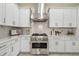 Modern kitchen with stainless steel appliances, white cabinets, and a stylish range hood at 2632 Tarragona Way, Wesley Chapel, FL 33543