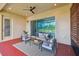 Covered patio with outdoor seating, ceiling fan, and sliding glass doors to the home's interior at 2632 Tarragona Way, Wesley Chapel, FL 33543