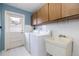 Laundry room featuring a washer, dryer, utility sink, and ample storage cabinets at 2932 Sweetgum S Way, Clearwater, FL 33761