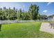 Lush backyard with green grass, white picket fence, and partial view of a screened-in lanai at 3211 Grassglen Pl, Wesley Chapel, FL 33544