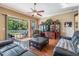 Bright living room with wood flooring, leather sofas, a ceiling fan, and access to the outdoor patio at 3211 Grassglen Pl, Wesley Chapel, FL 33544