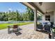 Covered patio with brick pavers, seating, and a view of the backyard and white picket fence at 3211 Grassglen Pl, Wesley Chapel, FL 33544