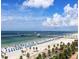 Expansive beach view with blue umbrellas, pier, and clear waters, perfect for vacation at 362 Coquina Dr, Tarpon Springs, FL 34689
