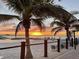 Beach scene with a beautiful sunset backdrop, palm trees and lounge chairs in the sand near a walkway at 362 Coquina Dr, Tarpon Springs, FL 34689