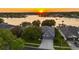 Stunning aerial view of lakeside property at sunset with mature trees and a two-car garage at 3829 Eagleflight Ln, Land O Lakes, FL 34639