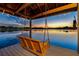 Enjoy lake views from the wooden swing on a covered dock, enhanced by charming string lights at sunset at 3829 Eagleflight Ln, Land O Lakes, FL 34639