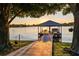 Dock at sunset over the lake featuring a covered seating area and boat slip at 3829 Eagleflight Ln, Land O Lakes, FL 34639