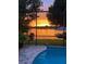 Relaxing pool area with a scenic sunset view overlooking the tranquil lake and dock at 3829 Eagleflight Ln, Land O Lakes, FL 34639