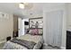 Cozy bedroom featuring a comfortable floral bed, light gray flooring, storage shelf over the bed, and gray curtains at 412 E Columbus Dr, Tampa, FL 33602