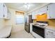 Cozy kitchen showcasing stainless steel refrigerator, electric range, and white cabinets at 4242 Sheldon Pl, New Port Richey, FL 34652