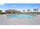 Community pool with a covered seating area, lounge chairs, and lush landscaping at 4951 Ribbon Rock Cv, Lakewood Ranch, FL 34211