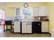 View of kitchen sink with white cabinets and black dishwasher, plus retro mosaic backsplash at 549 E Center St, Tarpon Springs, FL 34689