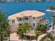 Waterfront home featuring a tile roof, manicured landscaping, private boat dock, and multi-level balconies overlooking the water at 6130 Kipps Colony W Dr, Gulfport, FL 33707