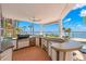 Outdoor kitchen with grill, sink, and bar area overlooking the waterfront at 6130 Kipps Colony W Dr, Gulfport, FL 33707