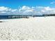 White sandy beach with clear blue water and a distant breakwater, ideal for relaxing and enjoying the ocean breeze at 6357 Spanish Main Dr, Apollo Beach, FL 33572