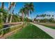 Community entrance showcases manicured landscaping with palm trees and 