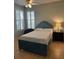 Bedroom featuring a blue upholstered bed, plantation shutters, and hardwood floors at 8618 Snowy Owl Way, Tampa, FL 33647