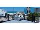 Relaxing rooftop deck with comfortable seating and ocean views of the beach and neighboring building at 9921 Gulf Blvd, Treasure Island, FL 33706
