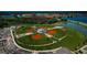Aerial view of a well-maintained community baseball field surrounded by lush landscaping and serene lake views at 12280 Lyon Pine Ln, Odessa, FL 33556