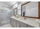 Bathroom with granite countertops, dual sinks, a glass-enclosed shower, and natural light at 12280 Lyon Pine Ln, Odessa, FL 33556