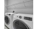 Laundry room with front-loading washer and dryer, shelving, and neutral wall color at 12280 Lyon Pine Ln, Odessa, FL 33556