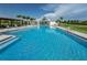 Resort style pool with a zero entry, multiple seating and lounge options, and lush landscaping surrounding the pool deck at 12280 Lyon Pine Ln, Odessa, FL 33556