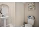 Modern half bathroom with pedestal sink, white toilet, tile floors, and decorative wall art at 13227 Great Plains Dr, Riverview, FL 33579