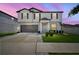 Two-story home features a well-manicured lawn, gray shutters, and a two car garage at dusk at 13227 Great Plains Dr, Riverview, FL 33579