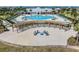 Aerial view of a community pool with ample lounge chairs, palm trees, and a modern fire pit area at 13511 Fladgate Mark Dr, Riverview, FL 33579