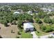 Scenic aerial view of a home with a light metal roof surrounded by lush trees and other houses in the neighborhood at 14319 Morristown Ave, Port Charlotte, FL 33981