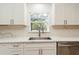 Bright kitchen view featuring a stainless steel sink, white cabinets and quartz countertops under window at 14319 Morristown Ave, Port Charlotte, FL 33981