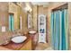 Bright bathroom with dual sinks, decorative mirror, travertine tile and walk-in shower at 18826 Huckavalle Rd, Odessa, FL 33556