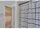 Neutral bathroom featuring a shower with a striped curtain, toilet, and window at 18826 Huckavalle Rd, Odessa, FL 33556