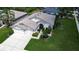 Expansive aerial shot of a well-maintained single-story home with lush green lawn, a two-car garage and mature landscaping at 1920 Folkstone Pl, Wesley Chapel, FL 33543