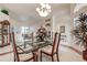 Formal dining room with glass table, chandelier lighting, and large floral centerpiece at 1920 Folkstone Pl, Wesley Chapel, FL 33543
