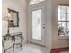 Bright foyer featuring neutral tile flooring, glass front door, decorative mirror, and transom window at 1920 Folkstone Pl, Wesley Chapel, FL 33543