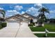 Charming single-story home featuring a well-manicured lawn, mature palm trees, and a convenient two-car garage at 1920 Folkstone Pl, Wesley Chapel, FL 33543