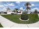 Well-manicured front lawn with tropical palm trees, landscaping, and a sidewalk at 1920 Folkstone Pl, Wesley Chapel, FL 33543
