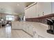 Bright kitchen with white cabinetry, decorative backsplash, breakfast bar seating, and open access to the living room at 1920 Folkstone Pl, Wesley Chapel, FL 33543