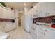 Efficient kitchen with white cabinetry, tile backsplash, white appliances, and tile flooring at 1920 Folkstone Pl, Wesley Chapel, FL 33543