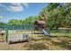 Community playground and tennis court featuring mature trees, play structures, and bench at 2725 14Th Ct, Palm Harbor, FL 34684