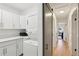 Laundry room with stackable washer/dryer, white cabinets and view to hallway with barn door at 3131 W Fielder St, Tampa, FL 33611