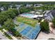 An aerial view of a community pool, clubhouse, basketball courts, and pickleball courts nestled within lush greenery at 4121 Highland Park Cir, Lutz, FL 33558